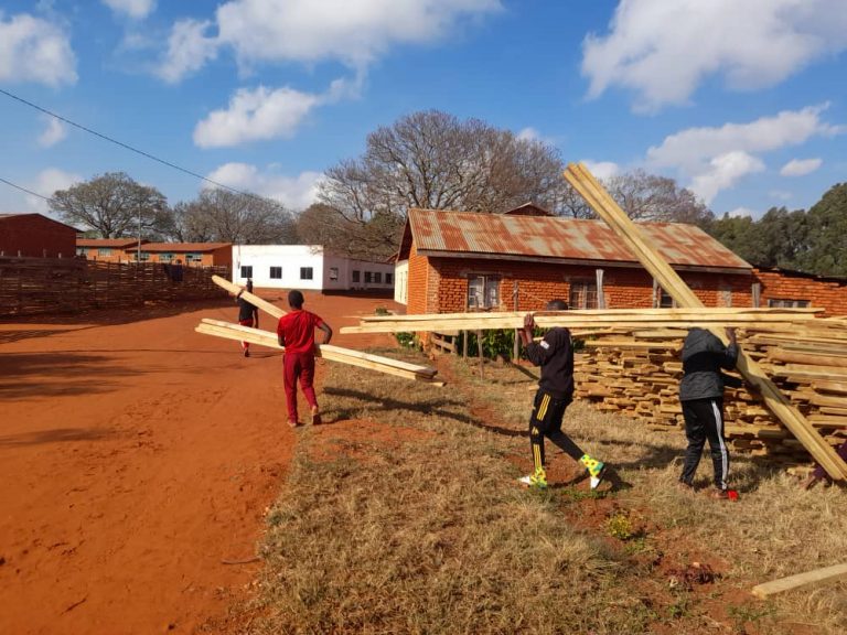 September 11, 2021: Students help carry treated wood being used for ceiling installation.